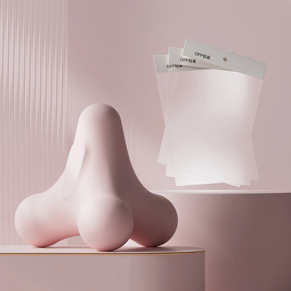 Pastel pink massage tool with floating OPP self-adhesive packaging sleeves in soft pink minimalist scene