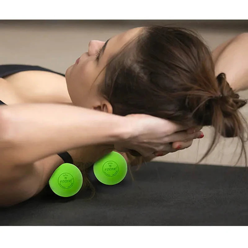 Individual lying on back using two green massage balls under shoulder blades for muscle tension relief